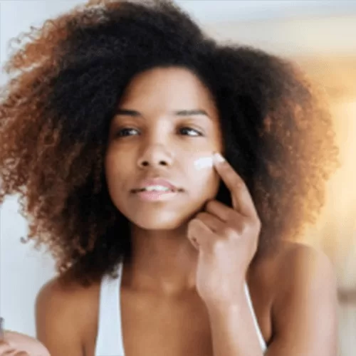 Chica aplicando crema nutritiva en el rostro como parte de su rutina de cuidado personal y bienestar natural