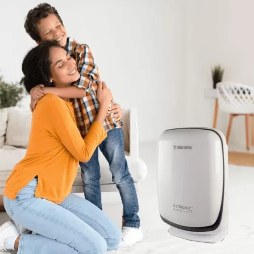 Madre abrazando a su hijo mientras sonríen al ver el filtro de aire Nikken, transmitiendo protección, salud y bienestar familiar